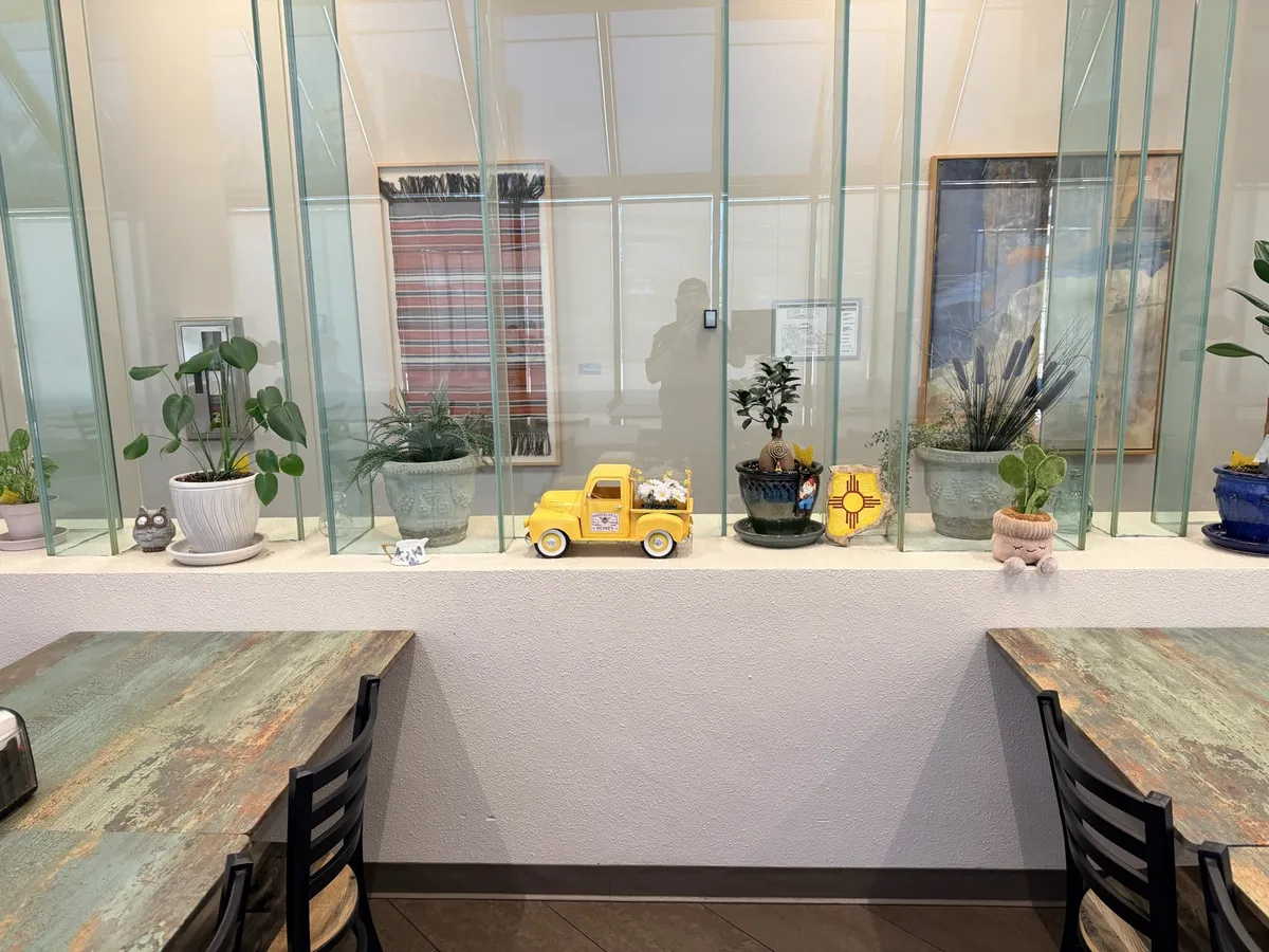 Potted plants, a small yellow toy truck and ceramics lined along the ledge between the tables and the lobby glass